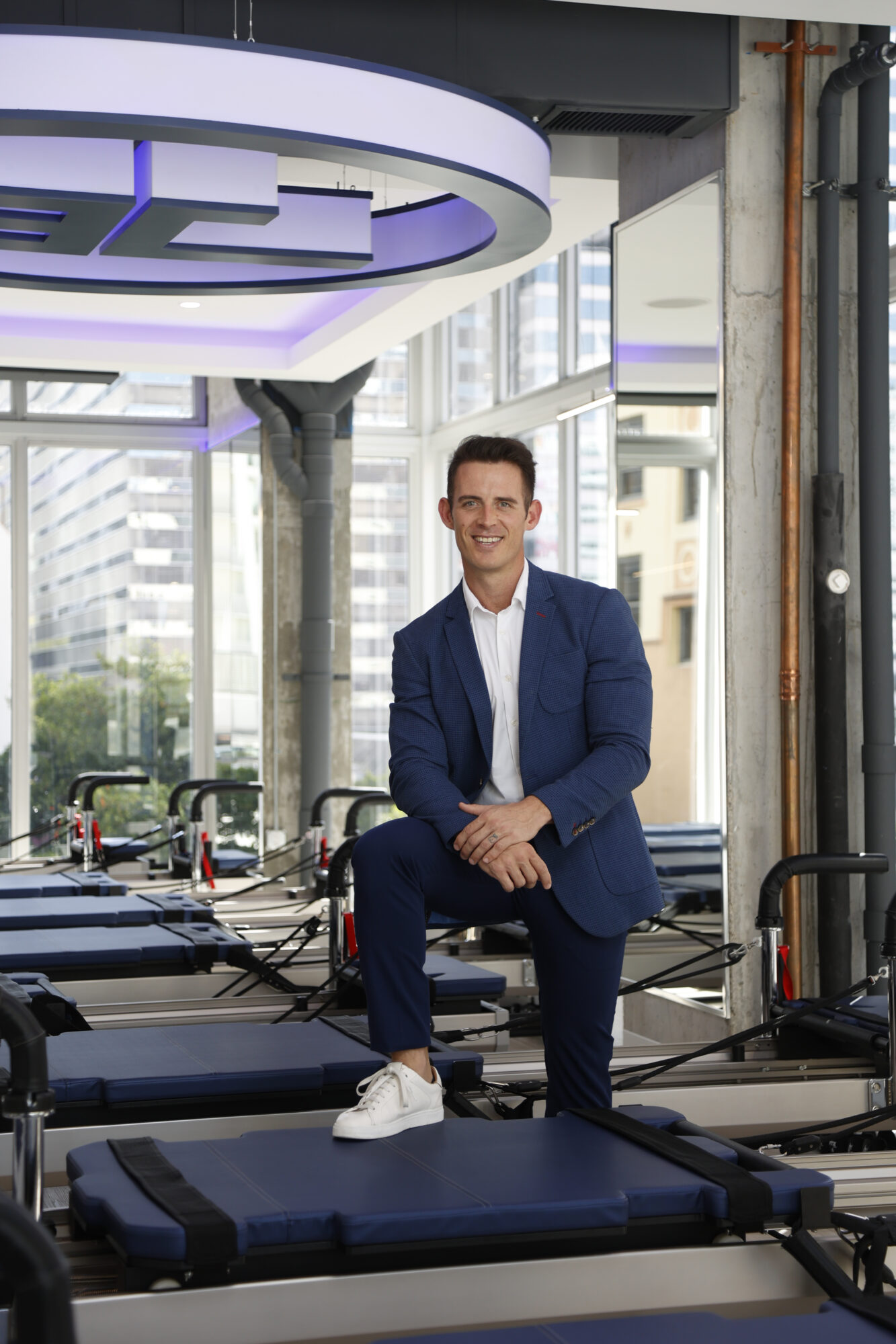 Bert Albertse standing in a JETSET Pilates studio, smiling with arms crossed in front of reformer machines