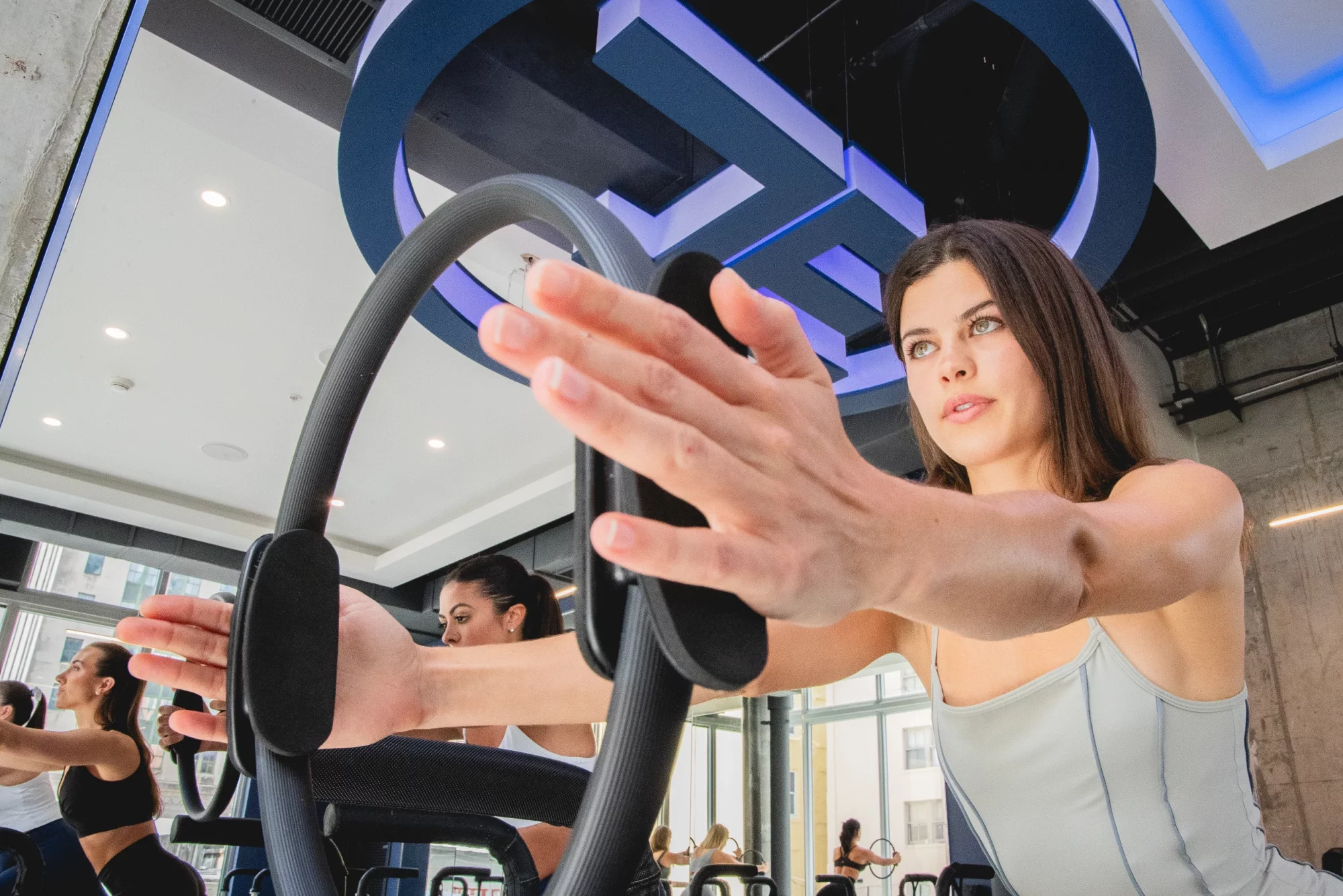 Woman reaching forward on a Pilates reformer during a workout at JETSET Pilates.